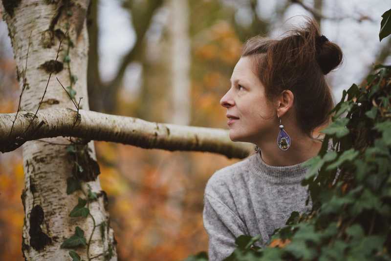 Mandy Falke im Profil zwischen herbstlichem Laub, den Blick nach oben gerichtet